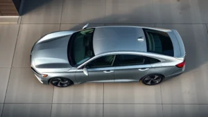 Professional overhead shot of sleek 2024 Honda Accord in metallic silver, photographed on polished concrete with modern urban background, showcasing sedan profile and design lines