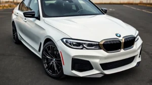 2024 BMW M340i xDrive sedan photographed from three-quarter front angle, alpine white paint, M Sport package, sharp focus on aggressive front bumper and headlight design, professional automotive photography studio lighting, clean asphalt background