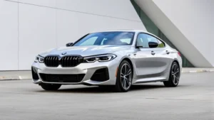 2023 BMW M440i xDrive luxury sedan photographed from three-quarter angle in silver metallic paint against modern architecture, showcasing sleek design and premium details