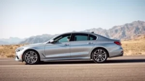 Sleek silver sedan photographed from three-quarter angle on open road with mountains in background, natural daylight, professional automotive photography