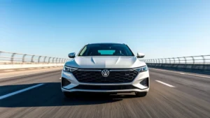 Premium 2024 sedan front three-quarter view on modern highway, sleek design, professional automotive photography, clear blue sky background, showcasing contemporary styling and aerodynamics