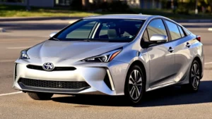 2024 Toyota Prius Prime in silver, three-quarter front view, modern sleek sedan design, parked on clean pavement with morning sunlight, hybrid badge visible, contemporary automotive photography style