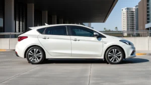 Modern compact sedan parked in urban setting with contemporary architecture background, professional automotive photography style, daylight, clean composition